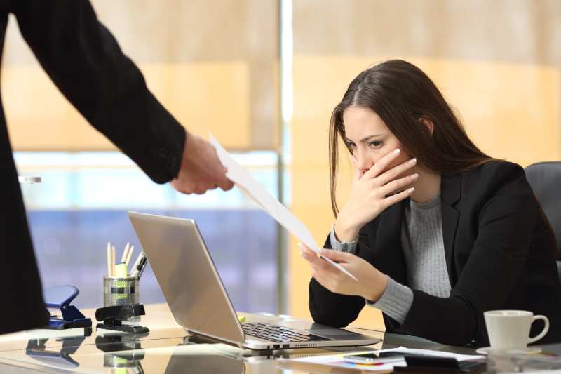 A woman appears upset as she is handed a dismissal notice