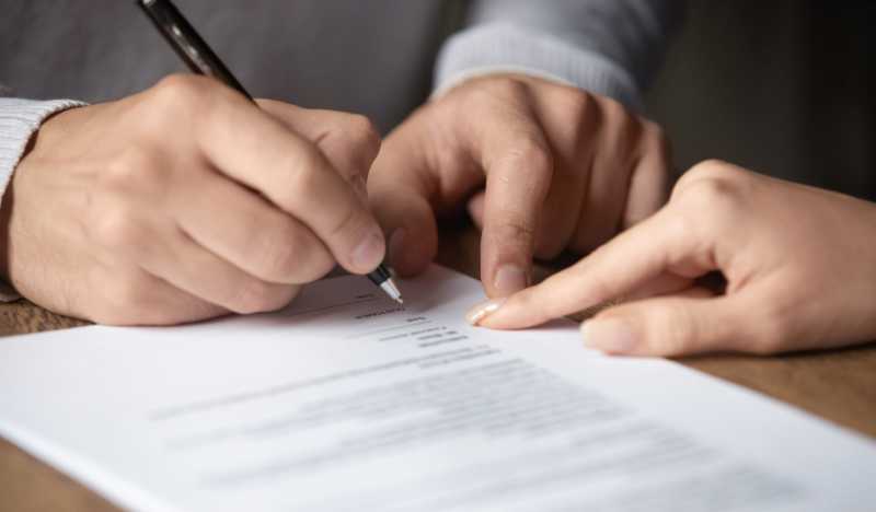 A female solicitor directs a client on where to sign a commercial dispute legal document