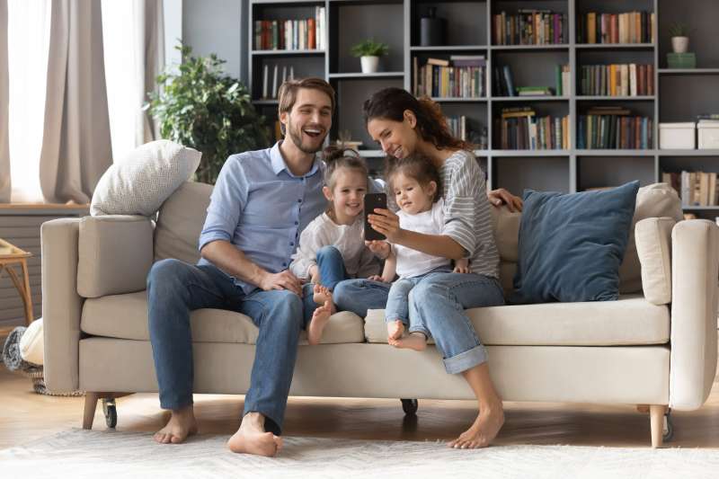 A young couple and their two daughters relax on the sofa