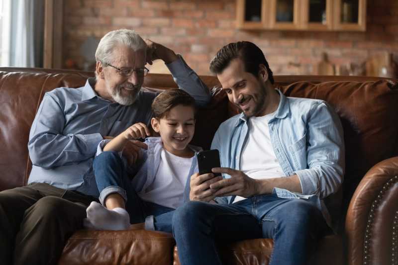 Three Generations of Family A grandfather, father and his son relax on the couch