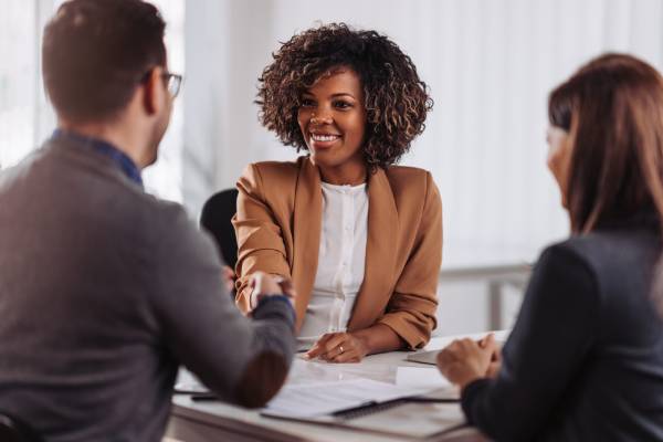 A interviewer shakes the hand of a woman after interviewing her in a bright modern office