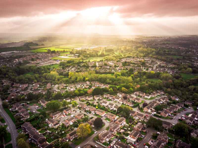 The sun bursts through the clouds over a large residential area