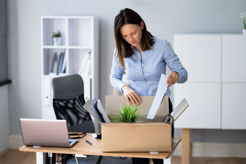 A female employee packs her things into a box after being dismissed at the office