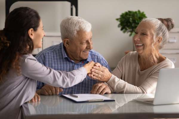 A cheerful elderly couple shake the hand of a solicitor during a probate consultation