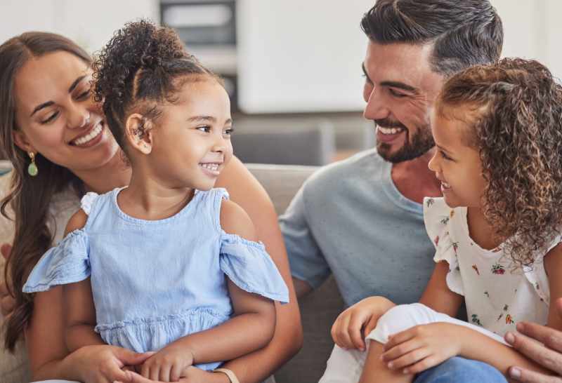 A young couple and their two daughters relax on the sofa